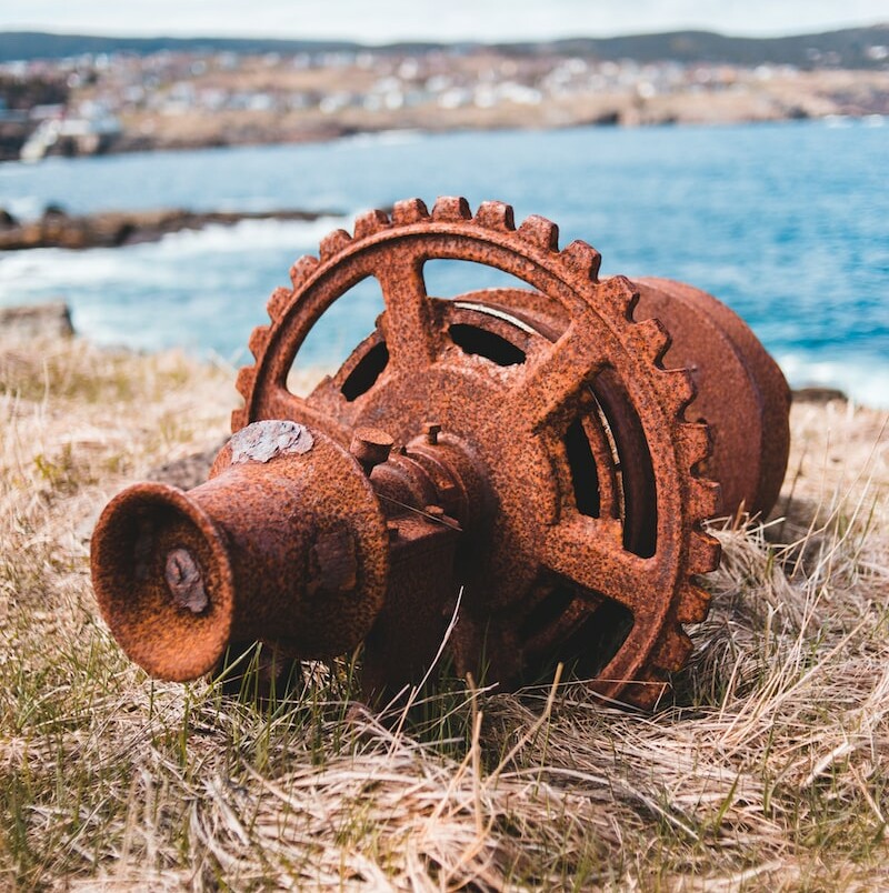 brown metal wheel on brown grass near sea during daytime