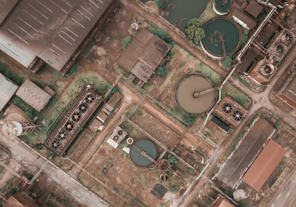 Drone view of shabby factory with round settling tanks with mechanical means removing solids in water treatment plant